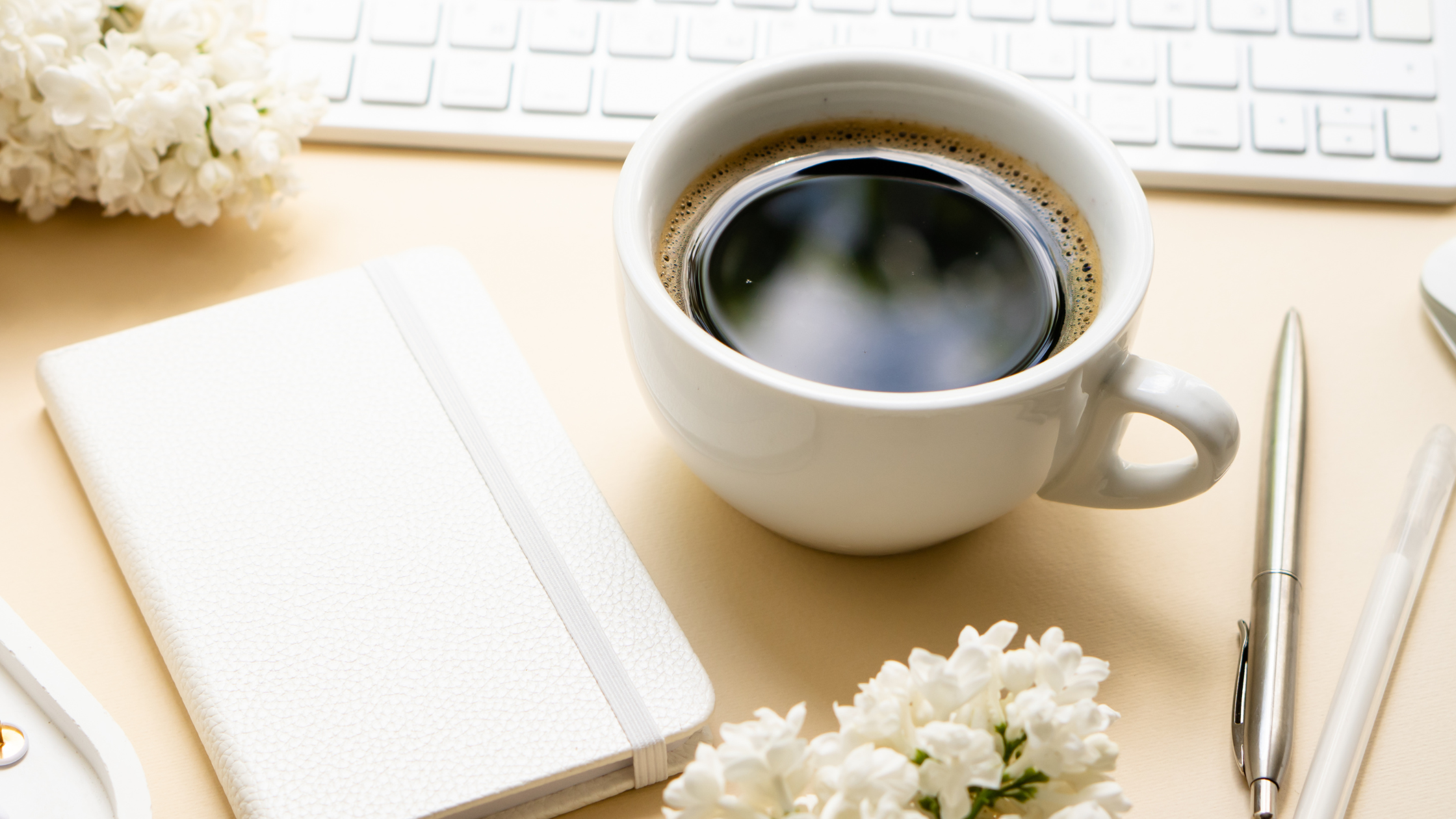 Coffee next to a keyboard and journal